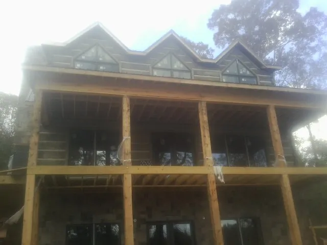 Dormers and porch framing on a large log home under construction — Roof Coating work by our crew in Hawkeye