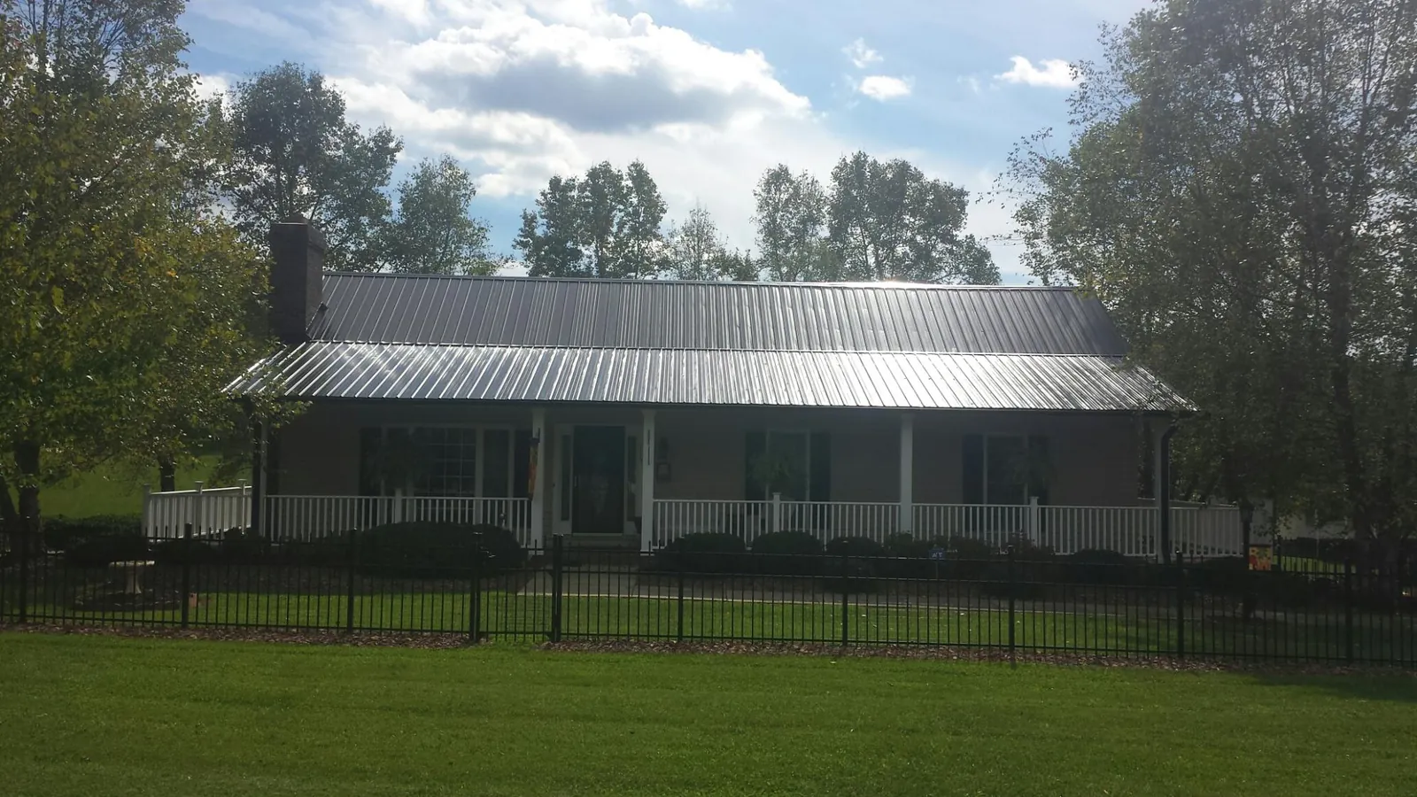 Gray metal roof on a brick ranch with a full width front porch — Gutter Guard Installation work by our crew in Hawkeye