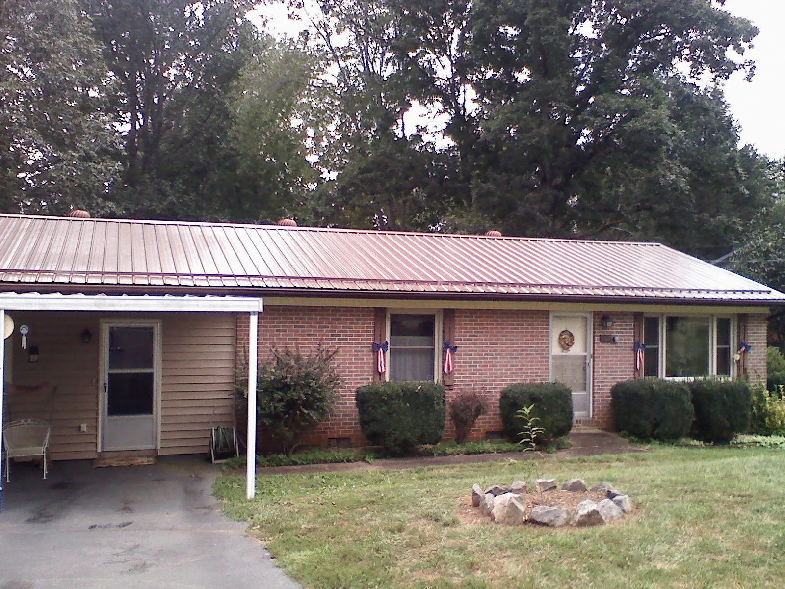 Bronze metal roof and carport on a brick ranch home — Roof Repair work by our crew in Hawkeye