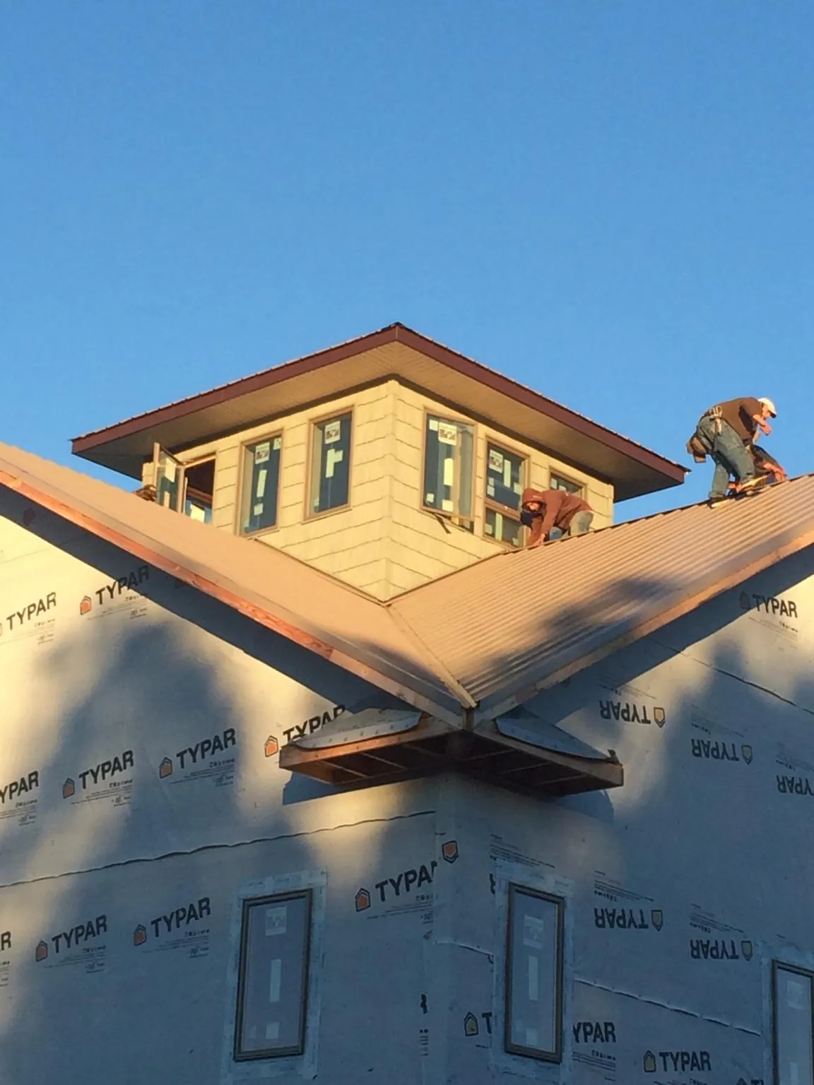 Roofers working around a rooftop cupola on a new metal roof at sunset — Roof Waterproofing in Hawkeye by Roofing Brothers